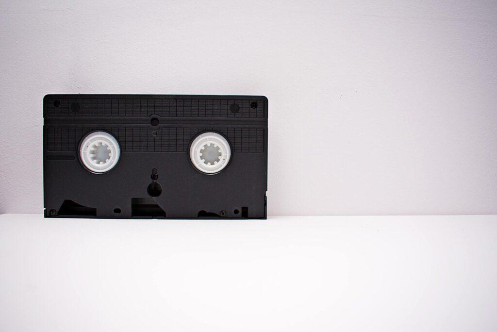 Schwarze VHS-Kassette auf weißem Hintergrund, Symbol für das Digitalisieren alter Medien, um wertvolle Erinnerungen zu bewahren.