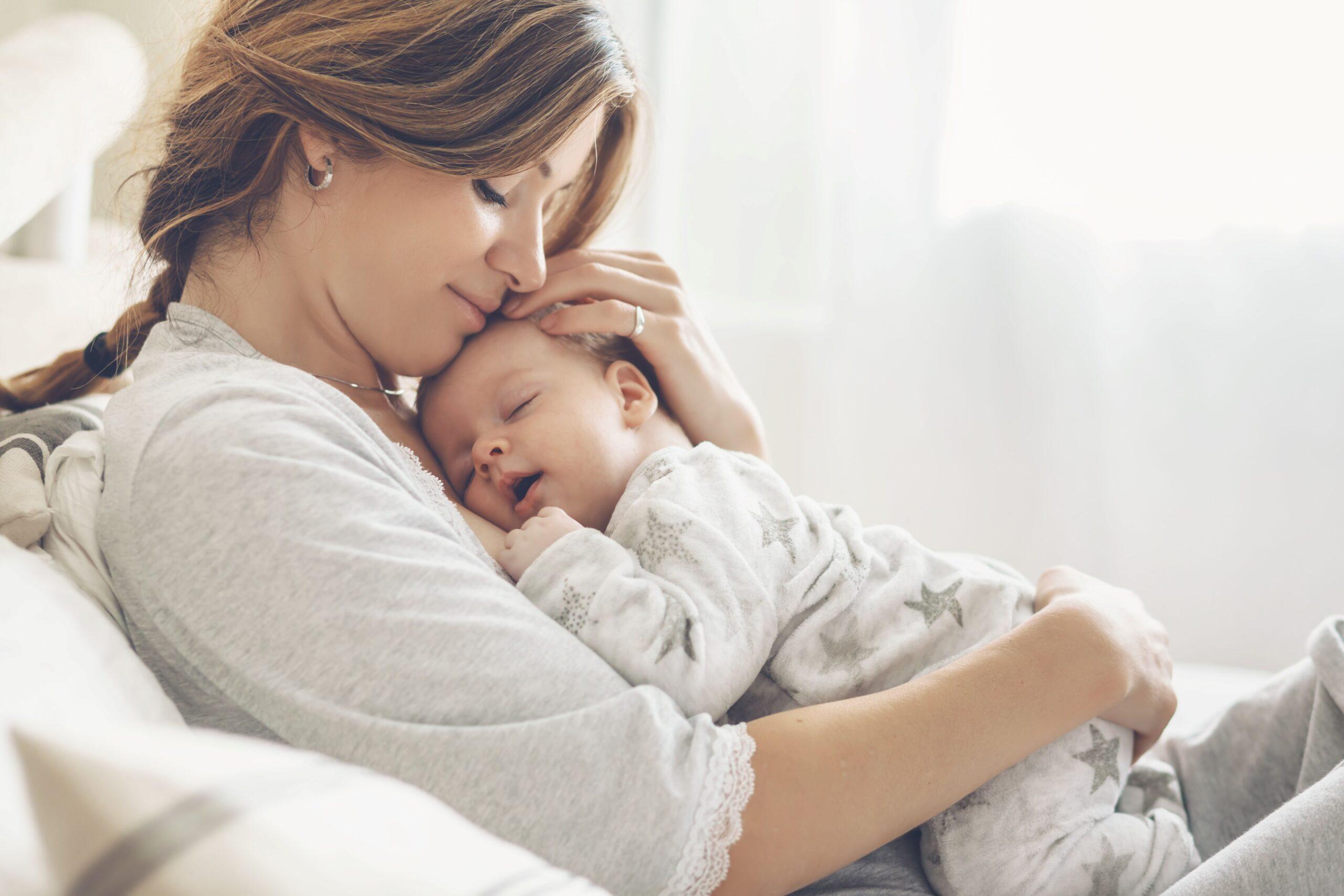 Eine Frau mit einem Baby im Arm, welches schläft.