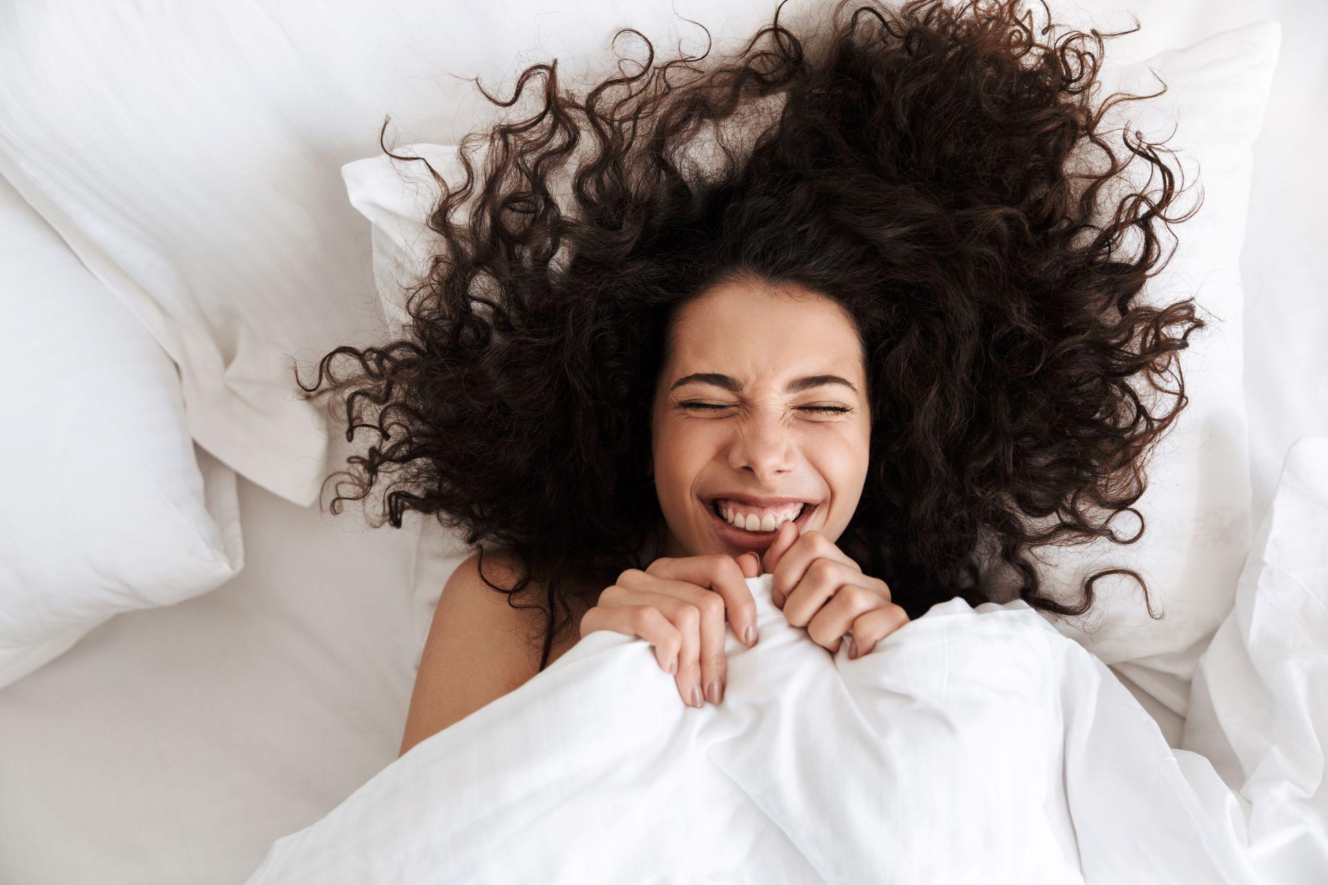 Eine Frau mit lockigen Haaren liegt im Bett