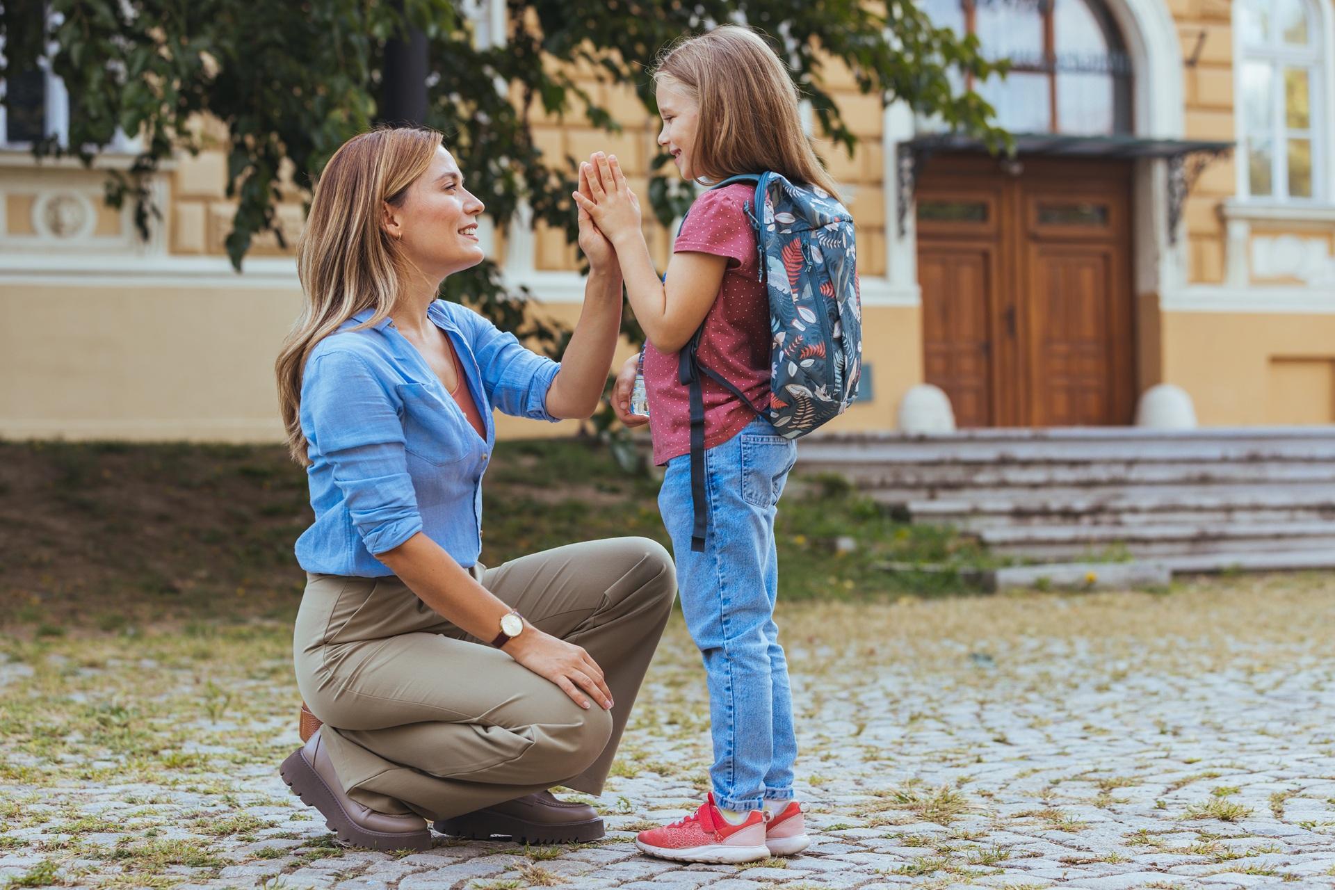 Mutter verabschiedet Tochter mit Rucksack vor Schule | Klassenfahrt München